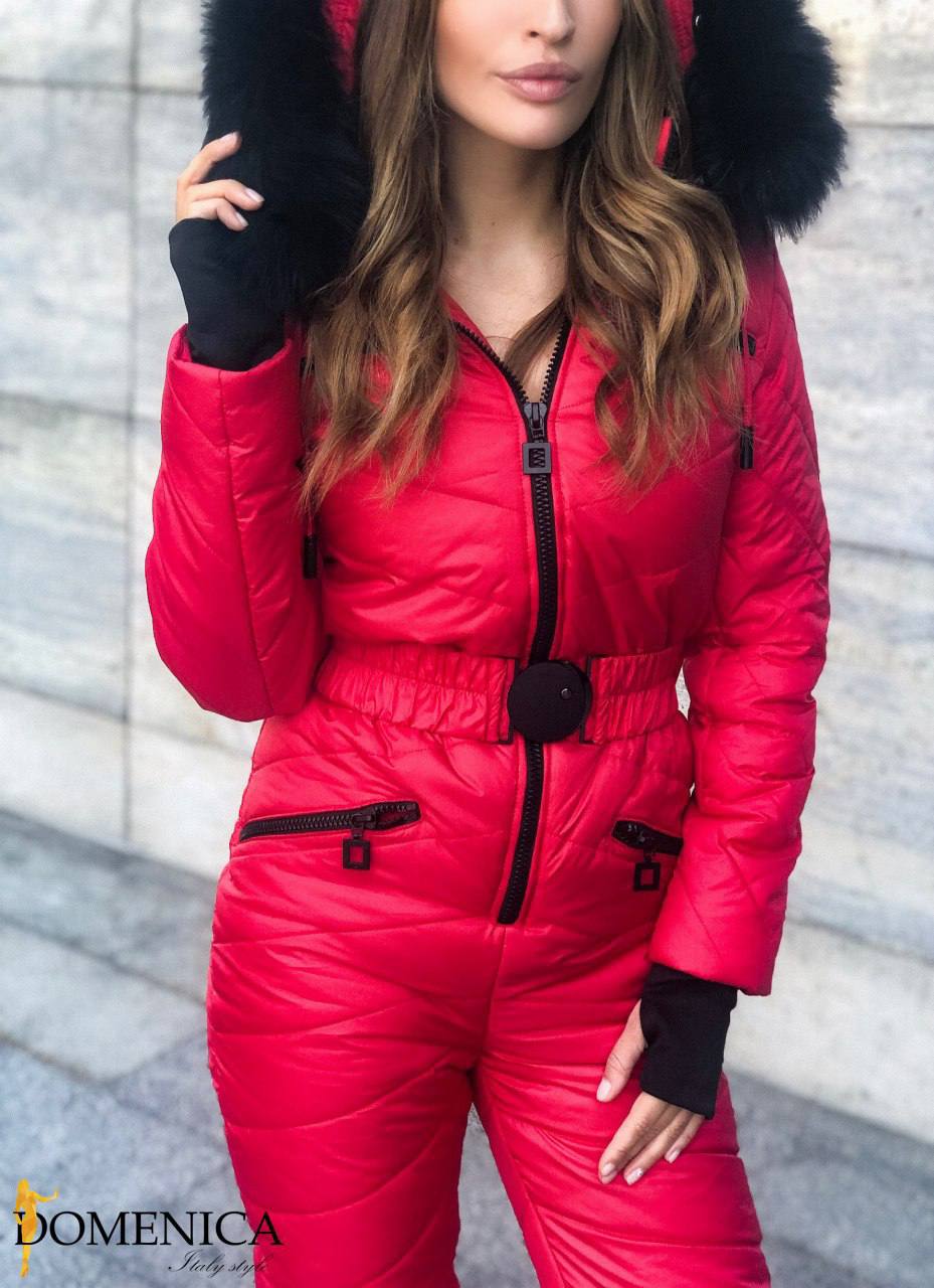 Person wearing a red puffer jumpsuit with black fur hood against a light gray background