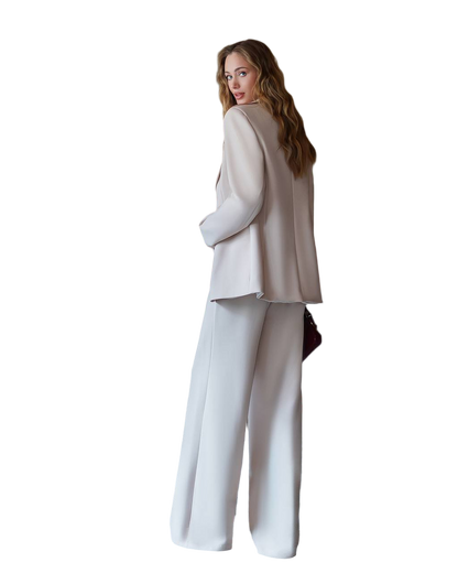 Woman wearing a beige blazer and white pants on a white background