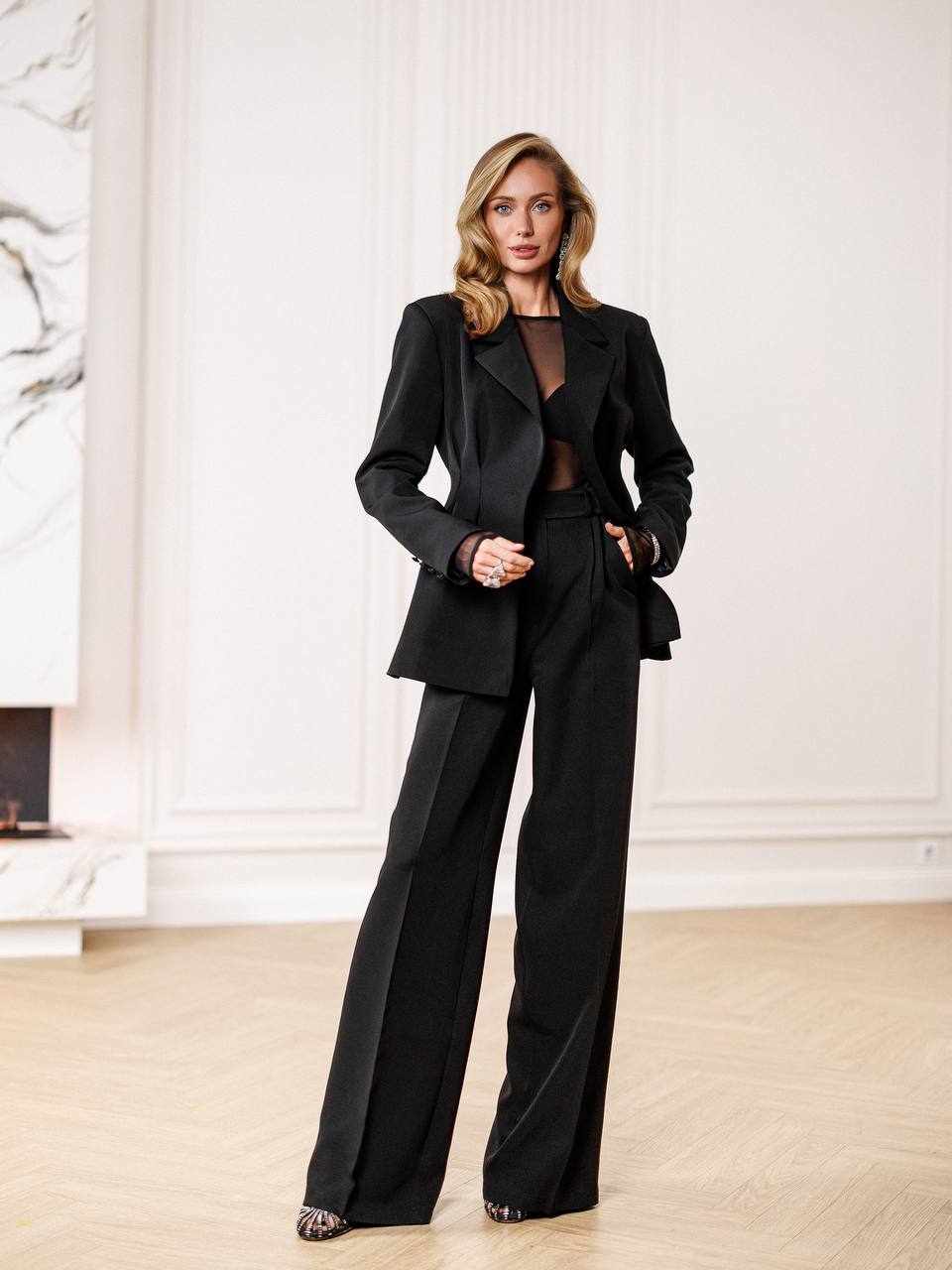 Woman wearing a black suit in an elegant room.