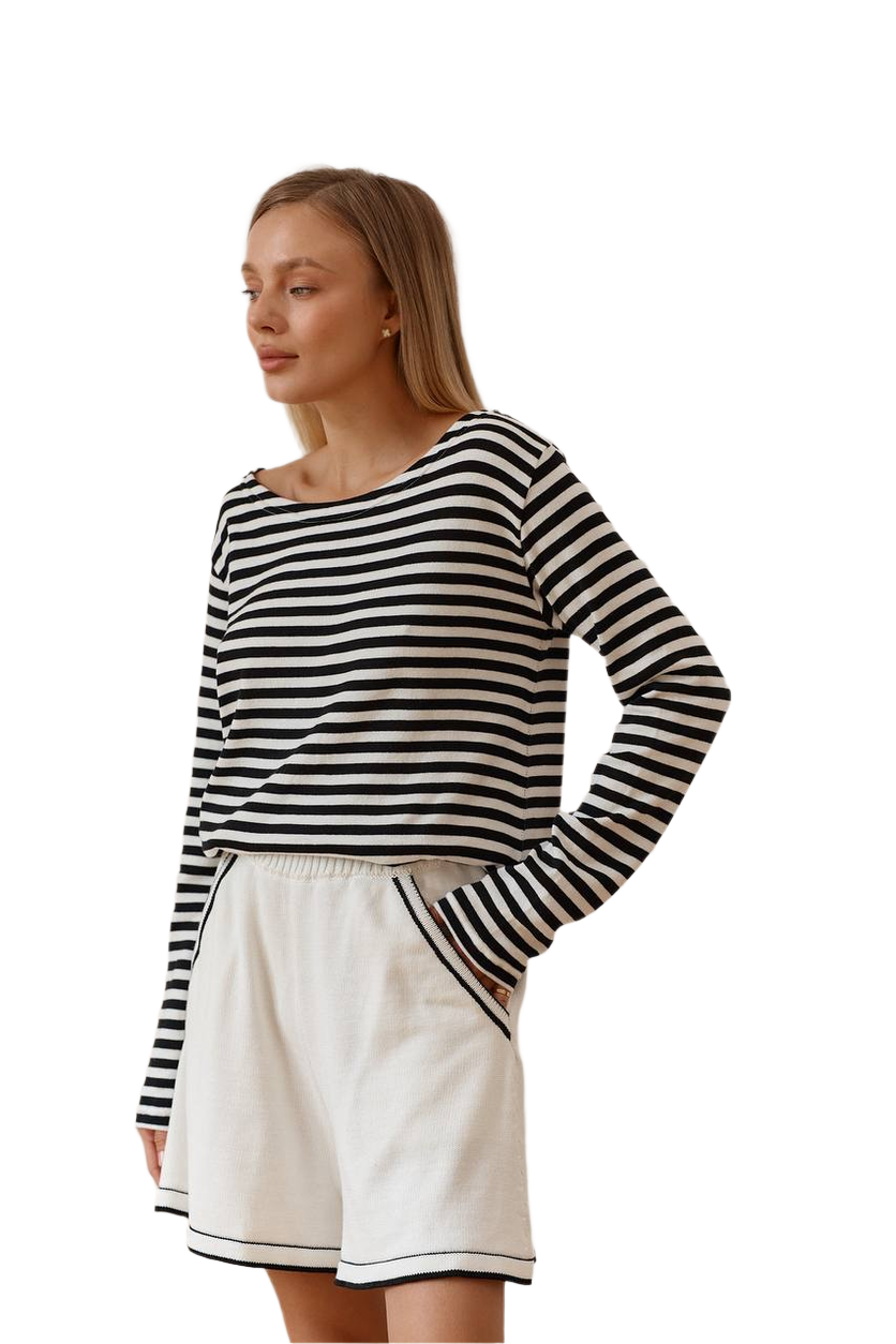 Woman wearing a black and white striped long-sleeve top and white shorts on a white background