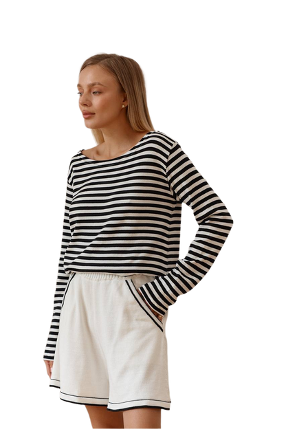 Woman wearing a black and white striped long-sleeve top and white shorts on a white background