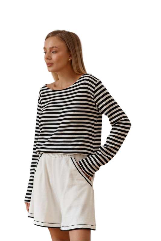 Woman wearing a black and white striped long-sleeve top and white shorts on a white background