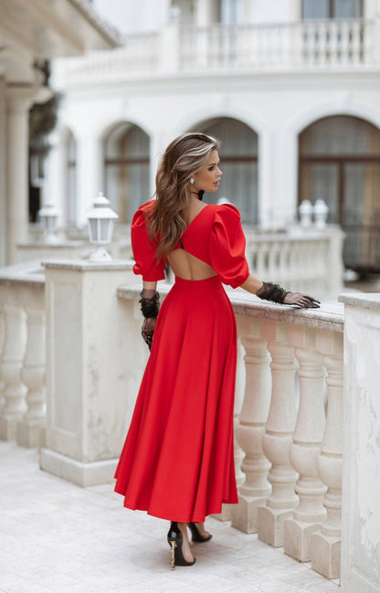 Woman in a red dress standing on a balcony with a white building in the background