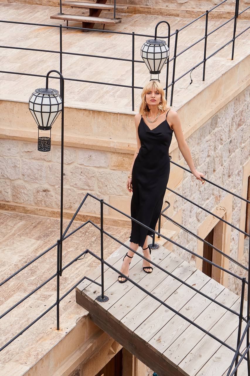 Woman in a black dress standing on a staircase with decorative lights.