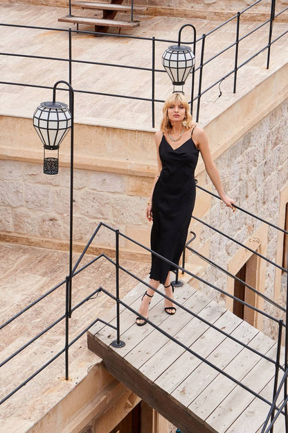 Woman in a black dress standing on a staircase with decorative lights.