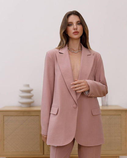 Woman wearing a pink suit standing against a neutral background