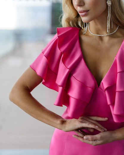 Close-up of a person wearing a bright pink ruffled dress with a blurred background