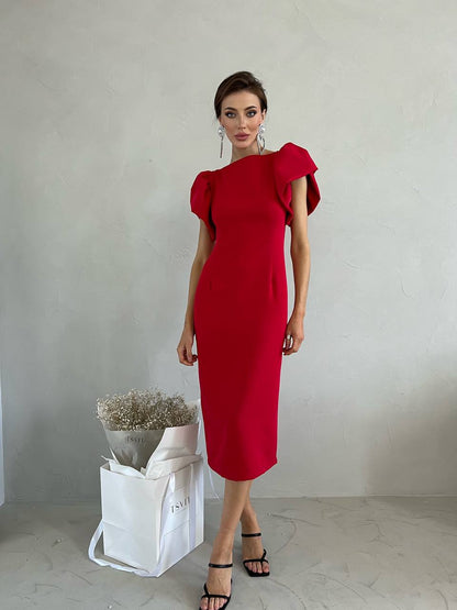 Woman wearing a red dress standing against a plain background