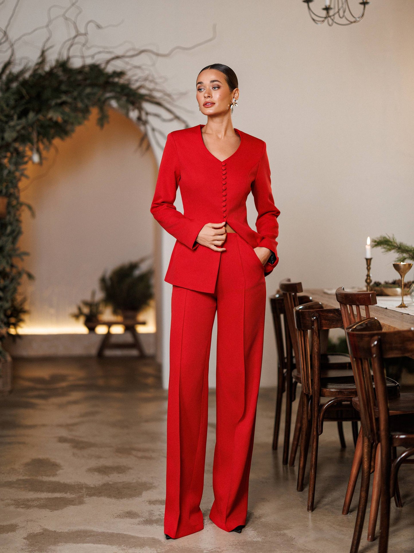 Woman in a red suit standing in a dining room setting