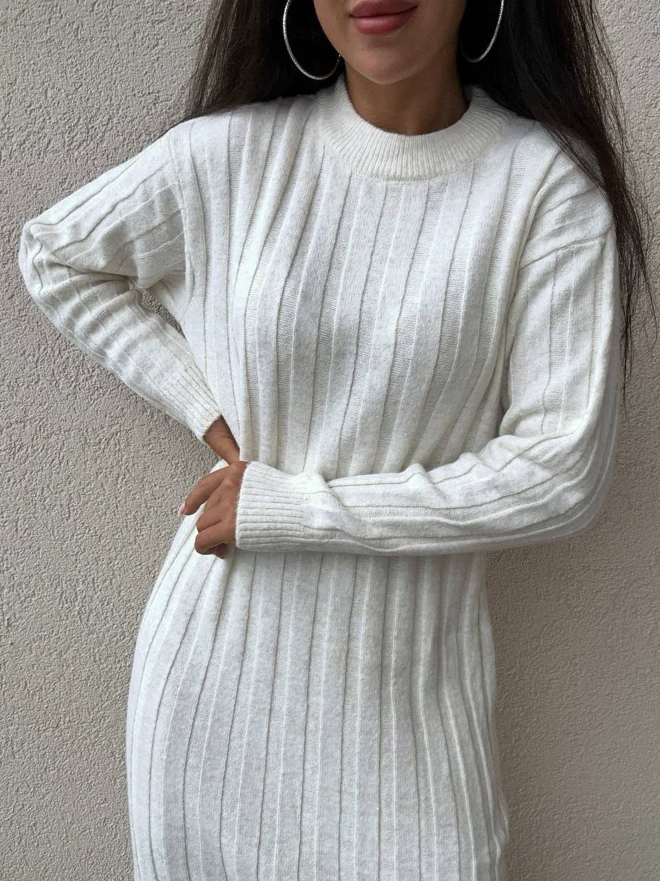 Person wearing a white ribbed sweater dress against a neutral background