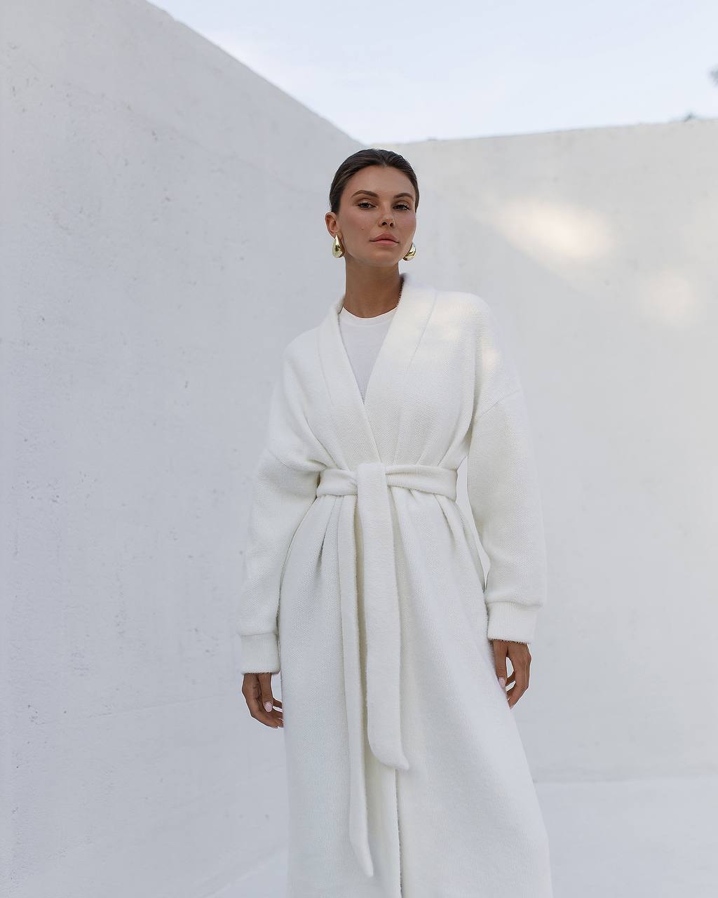Woman wearing a white robe against a plain background