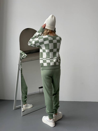 Person wearing a green and white checkered sweater and matching pants, standing in front of a mirror.