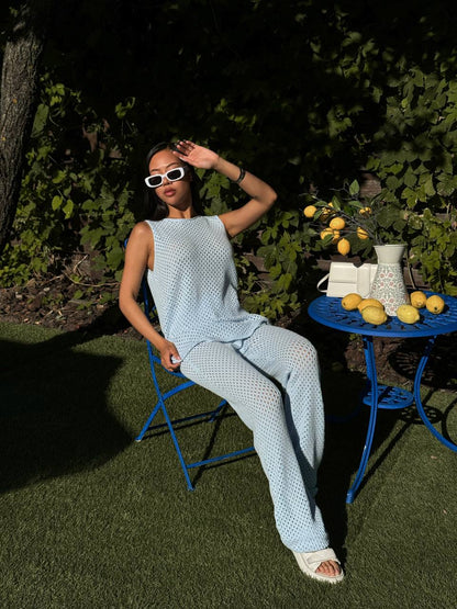 Woman in a light blue outfit sitting on a chair outdoors with a table of lemons nearby.