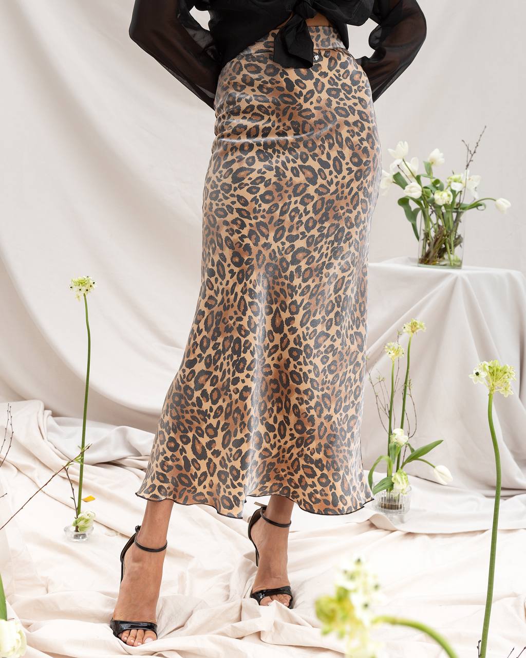 Person wearing a leopard print skirt with a neutral background
