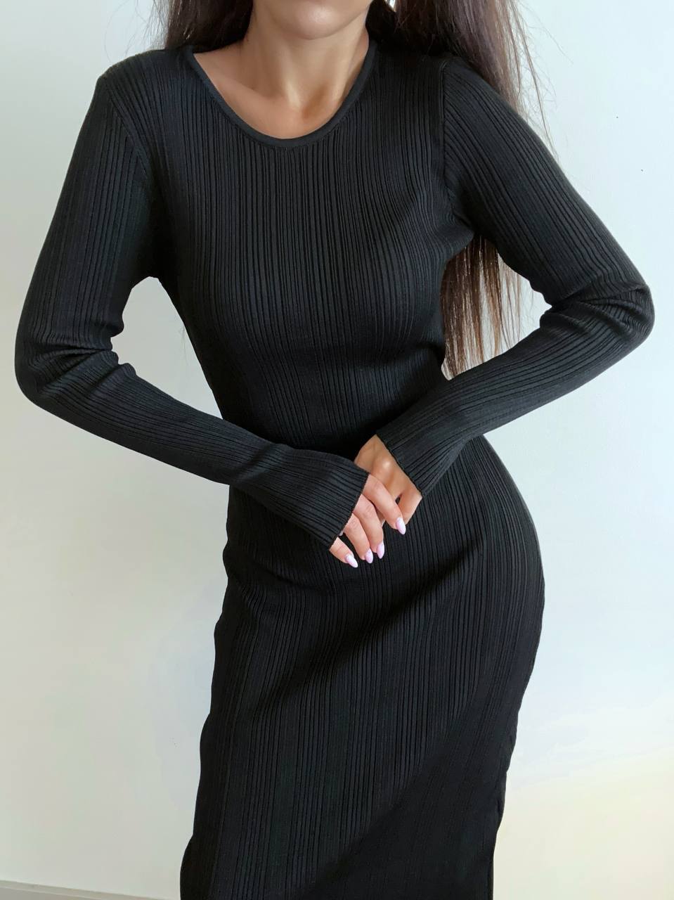 Person wearing a black ribbed dress against a plain background