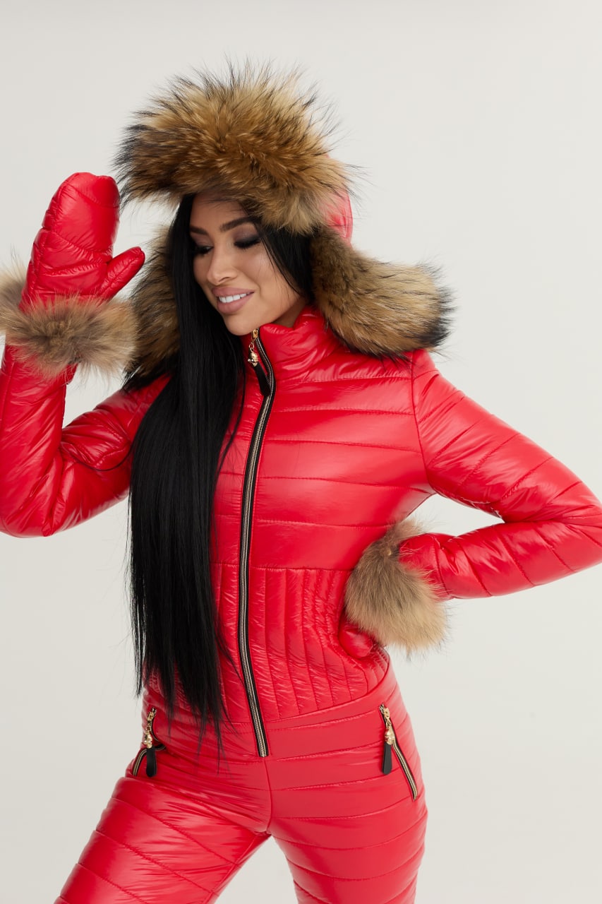 Person wearing a red puffer suit with fur hood and cuffs on a light gray background