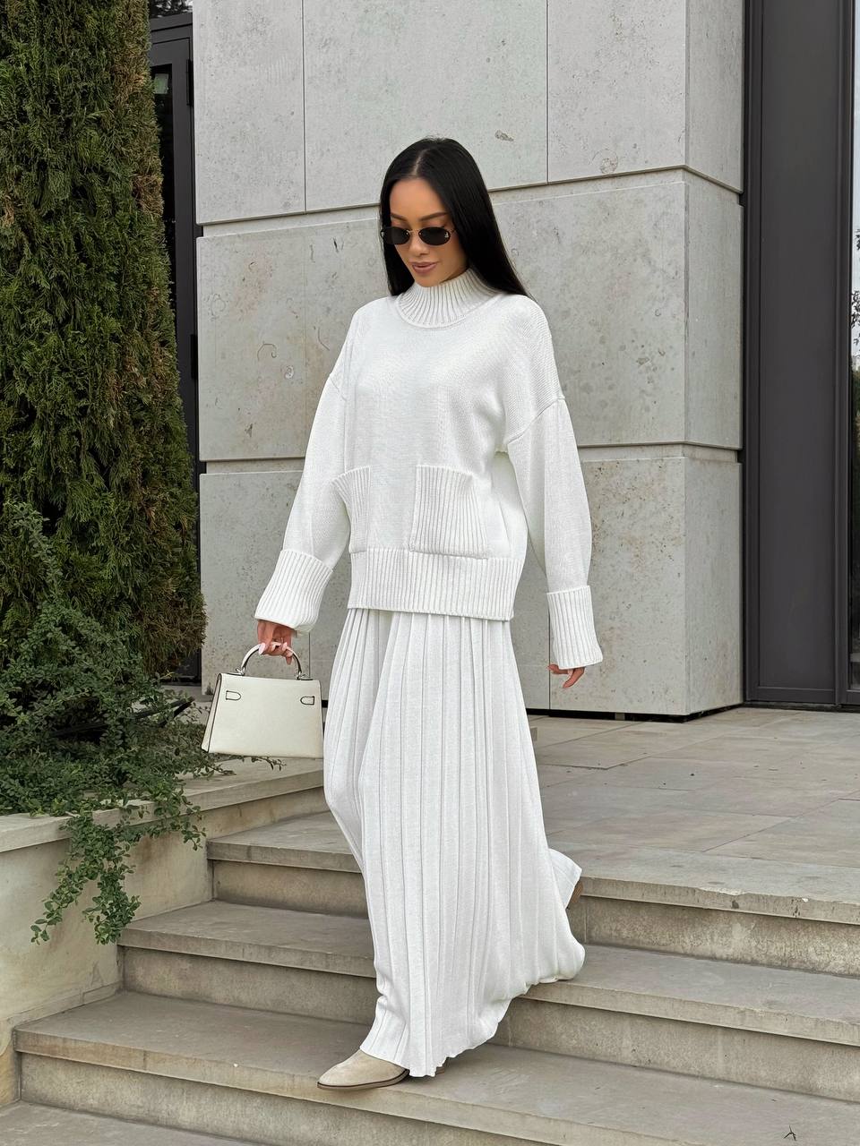 Woman in a white outfit standing on steps outdoors
