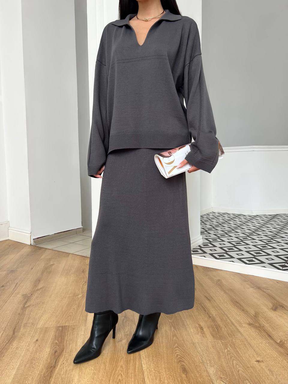 Person wearing a gray outfit with a long skirt in an indoor setting.