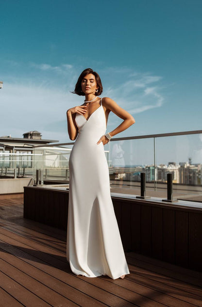 Woman in a white dress standing on a rooftop with a cityscape in the background