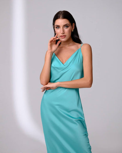 Woman wearing a turquoise dress against a gray background