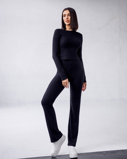 Woman wearing a black outfit with white sneakers on a plain background