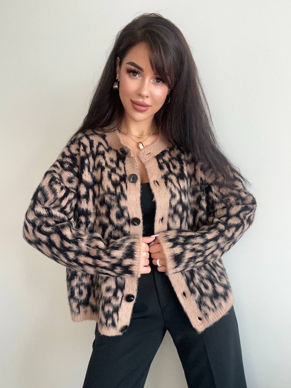 Woman wearing a leopard print cardigan against a plain background