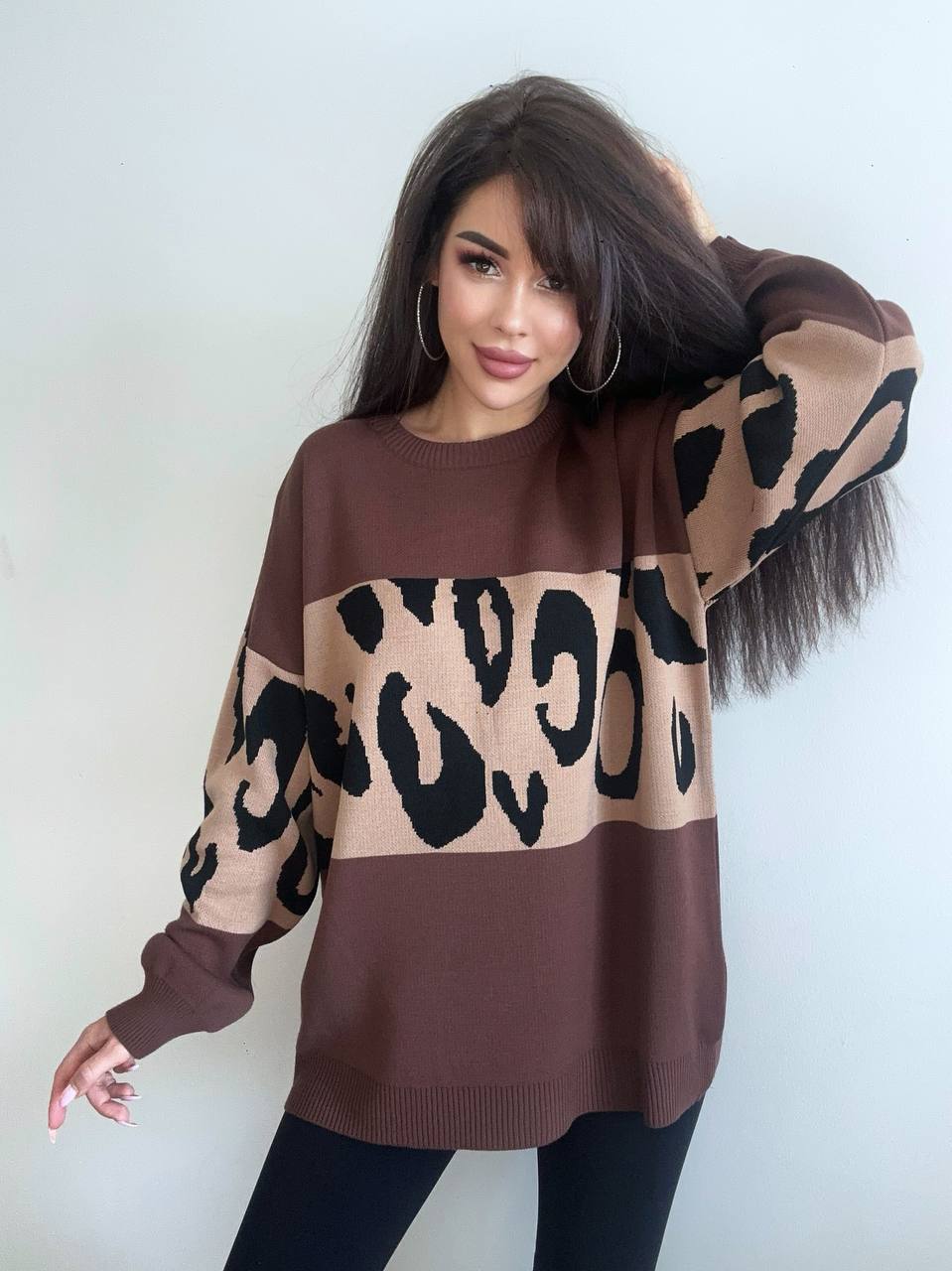 Woman wearing a brown sweater with leopard print pattern against a white background