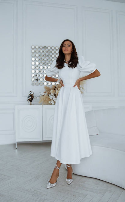 Woman wearing a white dress in a minimalistic room.