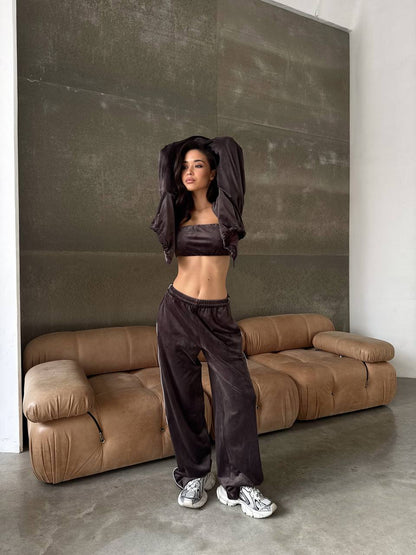 Woman in dark athletic wear standing in a modern room with a brown sofa.