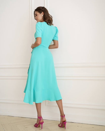 Woman wearing a turquoise dress with a plain white background