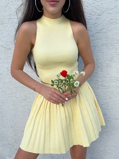 Woman in a yellow dress holding flowers against a gray wall