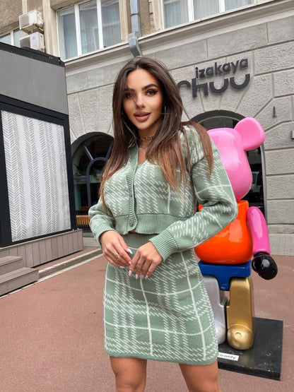Woman in a green outfit standing in front of a building with colorful sculptures.