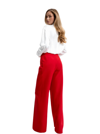 Woman wearing a white blouse and red pants on a white background