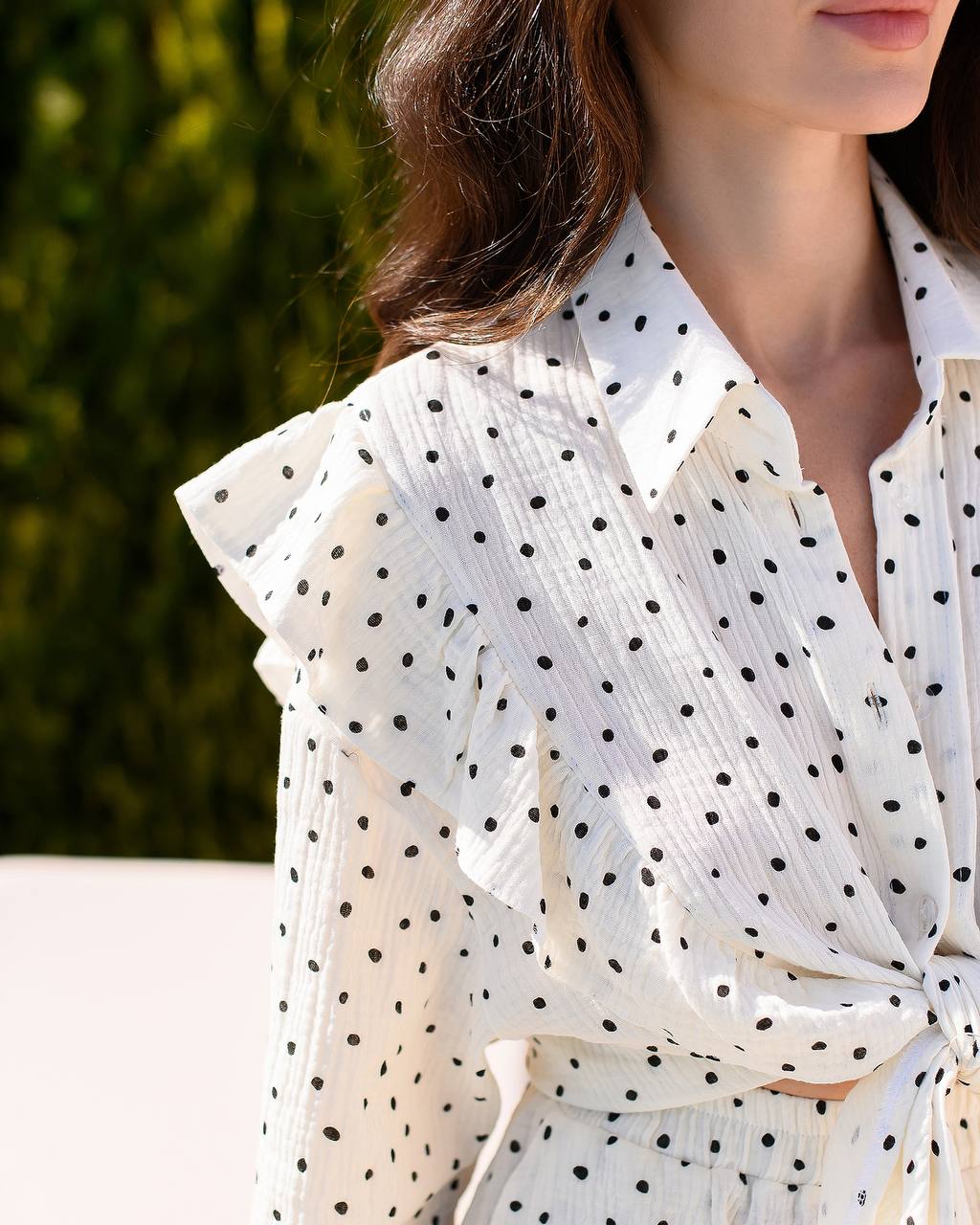 White polka dot blouse with ruffled sleeves worn by a person, blurred background