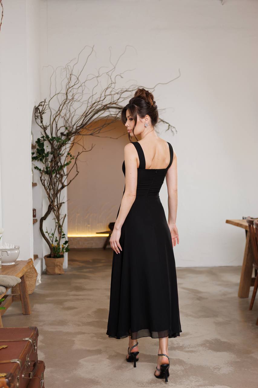 Woman in a black dress standing in a room with minimal decor