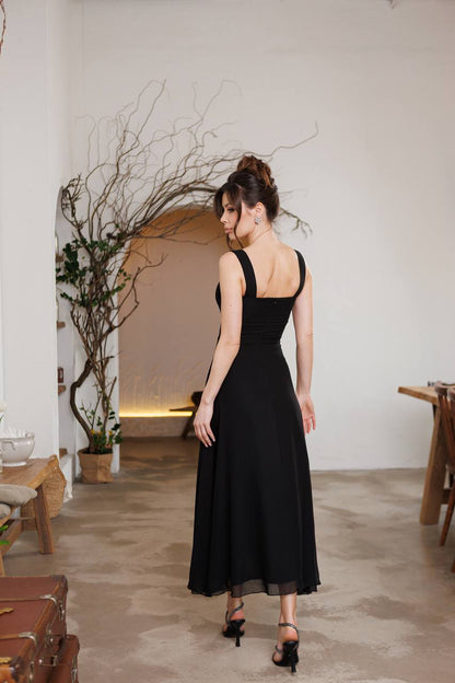 Woman in a black dress standing in a room with minimal decor