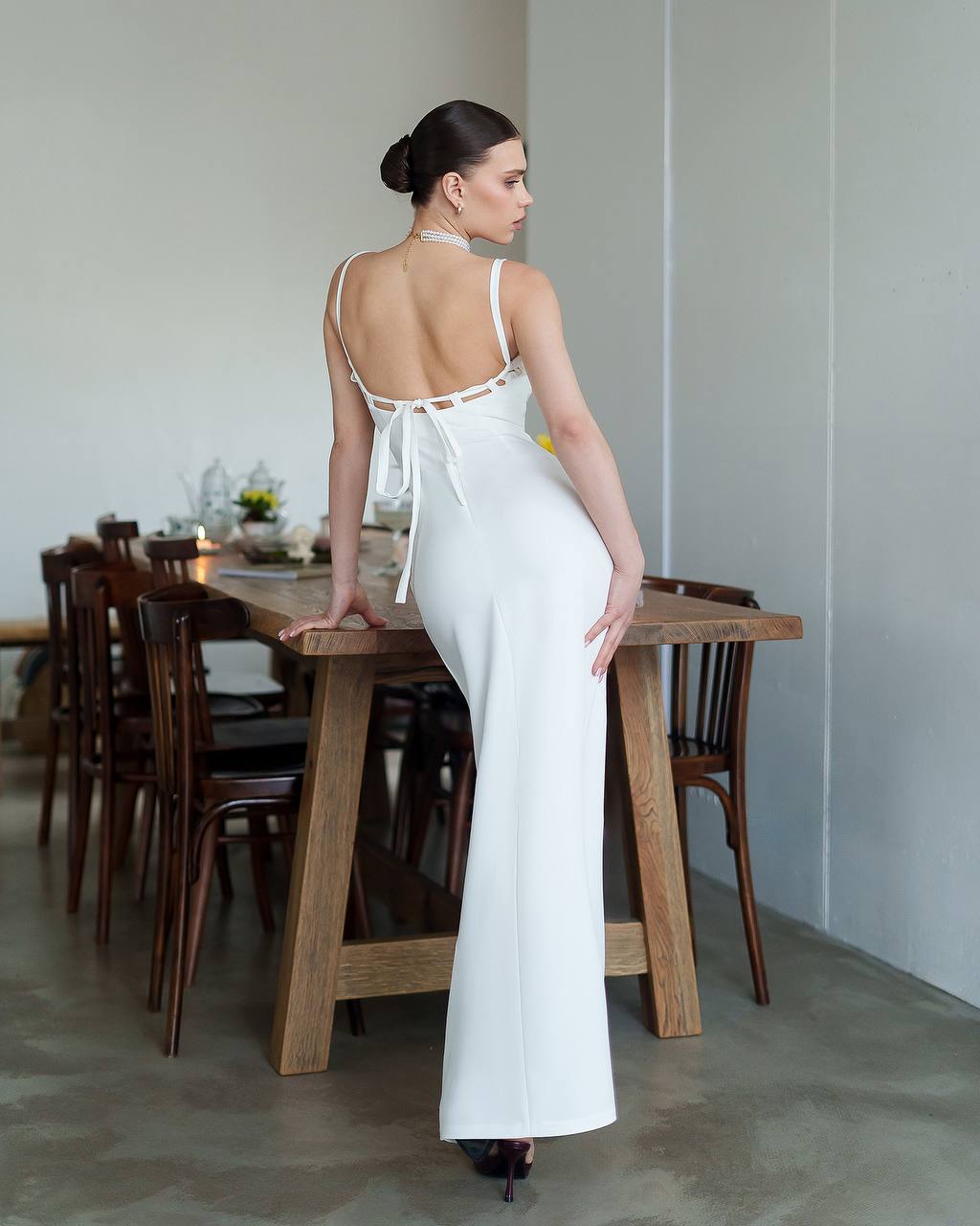 Woman in a white dress standing in a dining room.