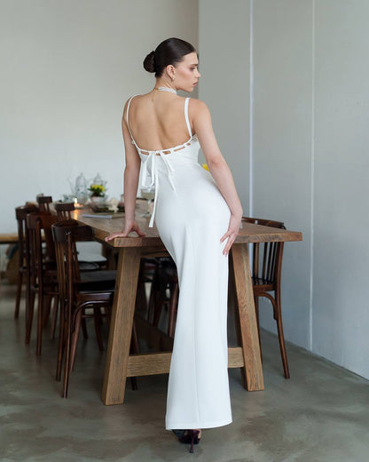 Woman in a white dress standing in a dining room.