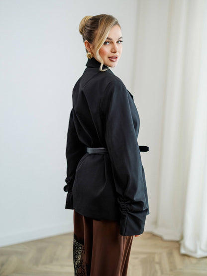 Woman wearing a black outfit with a high collar in a room with white curtains.
