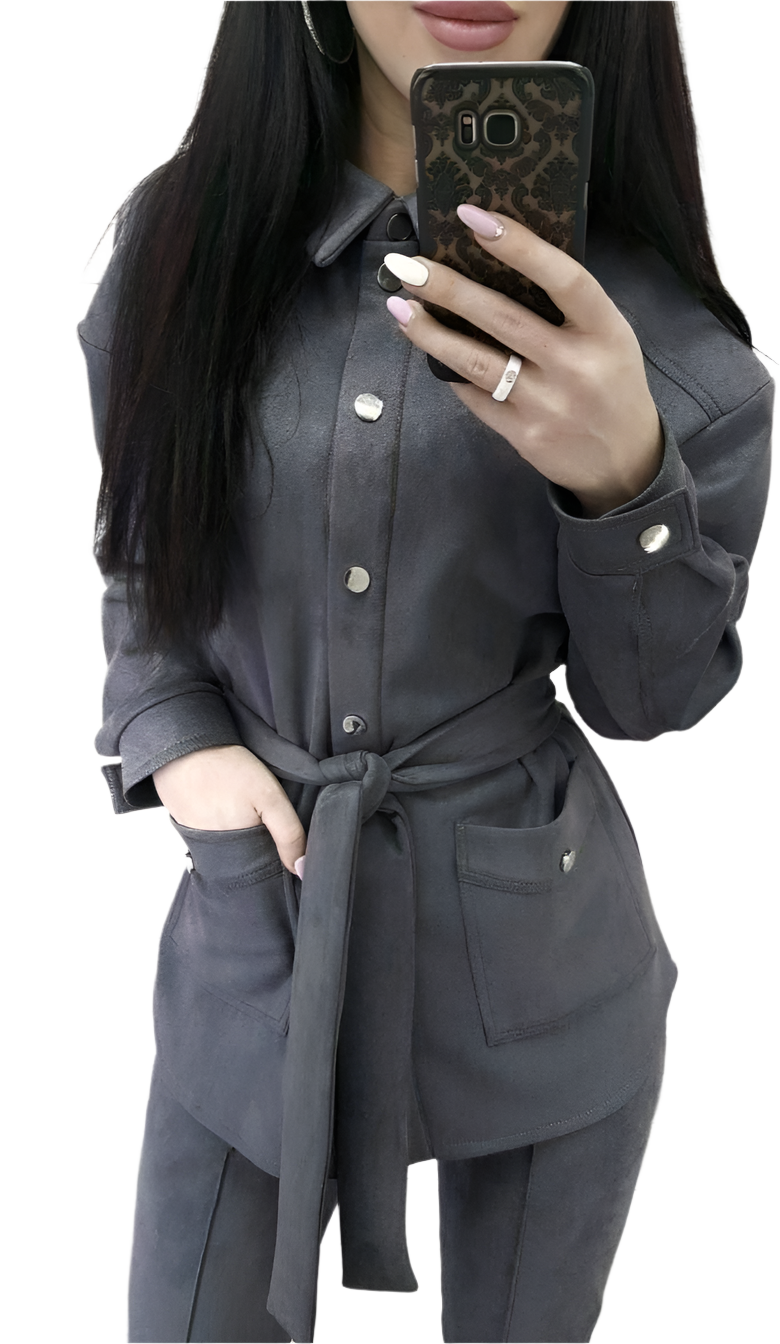 Person wearing a gray outfit with a belt, holding a phone.