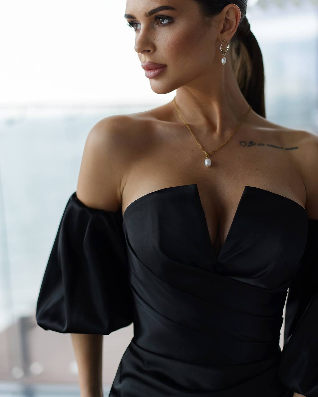 Woman wearing a black off-shoulder dress with a blurred background