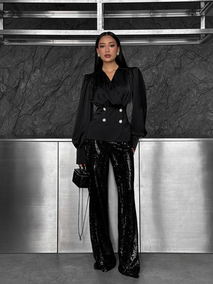 Person wearing a black outfit with sequin pants in an indoor setting