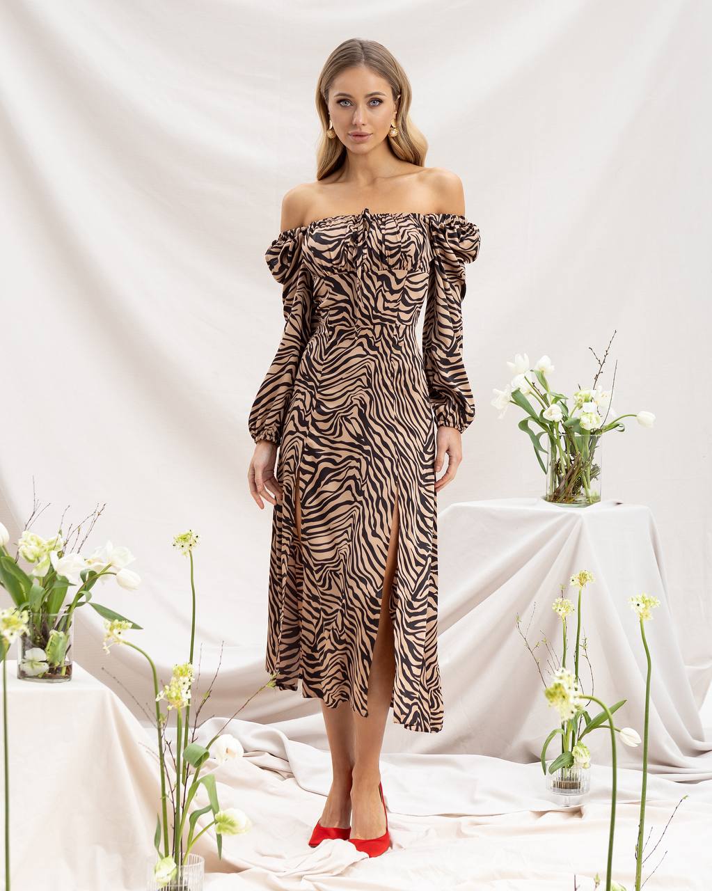 Woman wearing a zebra print off-shoulder dress with flowers in the background