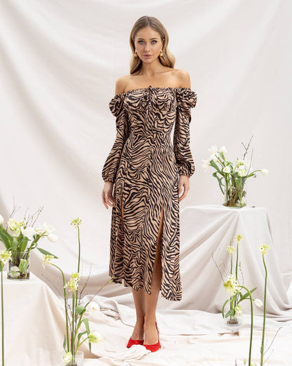 Woman wearing a zebra print off-shoulder dress with flowers in the background