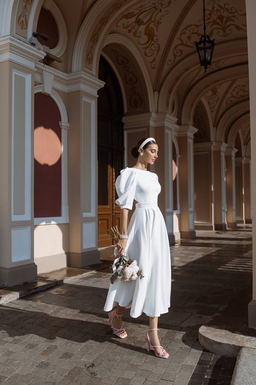 Woman in a white dress standing in an elegant architectural setting