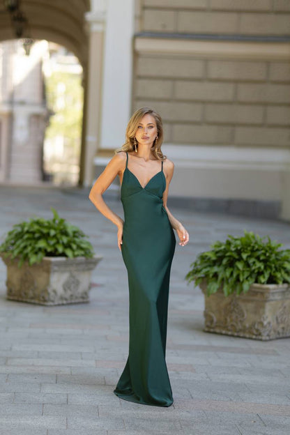 Woman in a green evening gown standing outdoors with classical architecture in the background