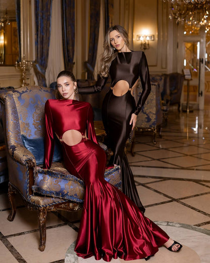 Two women in elegant evening gowns in a luxurious room.