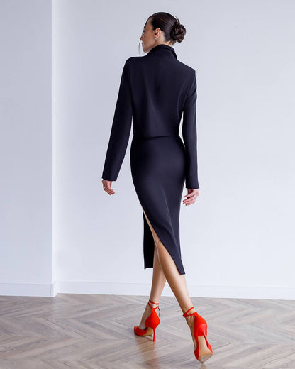 Woman wearing a black dress with a high slit and red shoes in a minimalistic setting