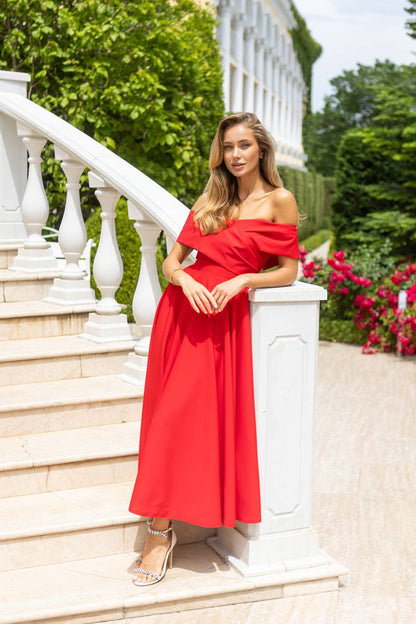 Woman in a red dress standing on white steps with greenery in the background