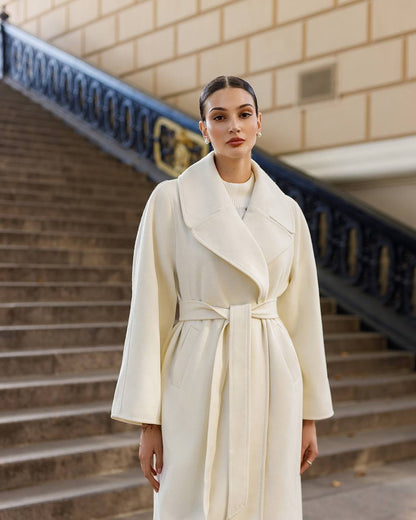 Woman wearing a white coat standing on steps with a building in the background